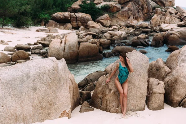 Playa secreta en un país tropical, en una isla donde no hay extraños, hermosa chica delgada descansa y disfruta de la belleza de las rocas y el mar azul . — Foto de Stock