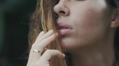 Kırpılmış bir çerçeve yakından görmek bir kız yüzü ağızlı bir yavaş çekim biraz zevk, uzun kirpik, çiller ve tabaklanmış deri kapalı gözleri ile açın. Bir modeli saç ile oynuyor