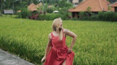 Bir ince kesilmiş spor gövdeli model nazik bir solo dans gerçekleştirir, uzun kırmızı bir elbise, saç eriterek bir saç modeli ve nazik bir makyaj, zarif hareketleri, yavaş dans çerçeveyi giymiş