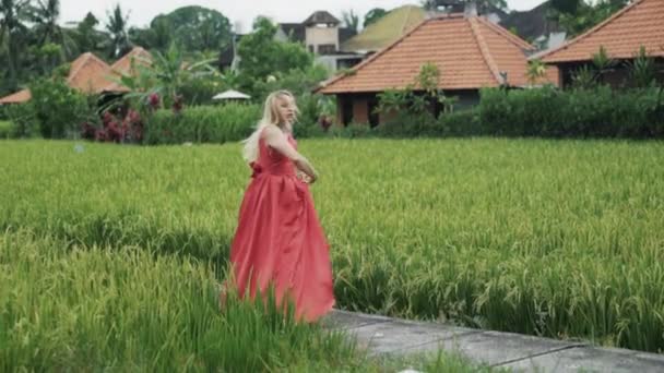 Lentamente disparando a una chica bailan en un vestido largo rojo con una falda exuberante. Una bailarina con un maquillaje natural, su cabello suelto hace que el cordel en el aire, con gracia levanta las manos, baila sensualmente . — Vídeos de Stock