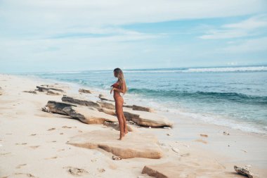 Seksi manken bir mayo profilinde standları ve ıssız bir beyaz plaj buzlu hayran. Dinlenmek için bile bir tan ve güzel bir vücut bir kızla geldi.