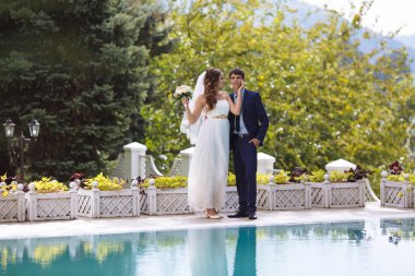 Bir kız bir gelinlik hafif bir buket çiçek tutan ve yavaşça bir iş takım elbise giymiş adamın yüzünü dokunuyor. Düğün kavramı.