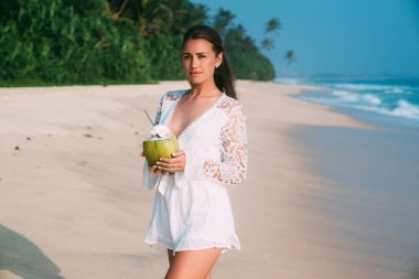 İnce uzun boylu güzel esmer adalarda dinlenmek için geldi, beyaz kumlu plaj boyunca yürüyor, hafta sonu sahiptir. Palmiye ağacından kesilmiş taze Hindistan cevizi içecekler, günlük beyaz giysiler giyer