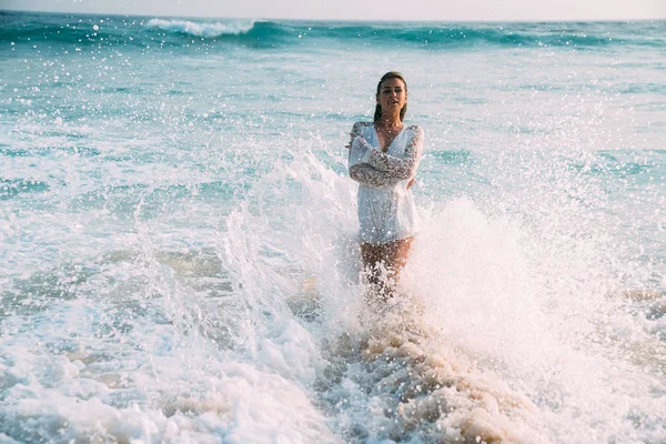 Bir genç kızın yakın çekim deniz sprey ve bel su, köpük giymiş kendini, geri kalan zevk sarılma bir beyaz şık elbiseli