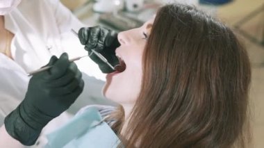 Kırpılmış bir çerçeve bir close-up bir yavaş hareket kurşun bir genç kızın bir dişçiye rutin muayenede geldi. Uzman diş bir ayna ve bir mala yardımı ile hastaların diş hileler
