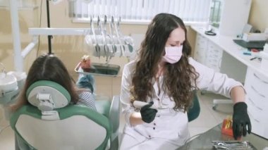 Yakın çekim ağır çekim çekim steadicam Doktor dişçi diş matkap ve diş ayna kullanır, onun hasta için dişli iyileştiriyor. Doktor, office bir koltukta kız yatıyor geldi çürüğü tedavi etmek için