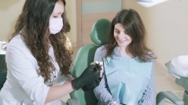 Yavaş yavaş çekim hasta hastanede diş sandalye doktor ofisinde oturuyor, diş hekimi diş yapısı hakkında her şey insan dişleri model üzerinde gösterir söyler.