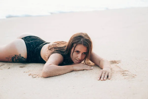 Das Konzept der Freizeit, des Reisens, des Vergnügens, des Urlaubs, des Menschen. eine junge Europäerin stieg gerade aus dem Wasser, badete, legte sich auf den warmen Sand. Gesicht eines jungen Mädchens im Sand beim Sonnenbaden auf der — Stockfoto