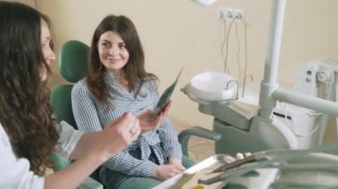 Yavaş yavaş çekim steadikam kız bir diş hekimi doktor ofisinde doktoru tavsiye için dinler, X-ray görünüyor. Doktor nedenini açıklamak için diş bir mock-up alır