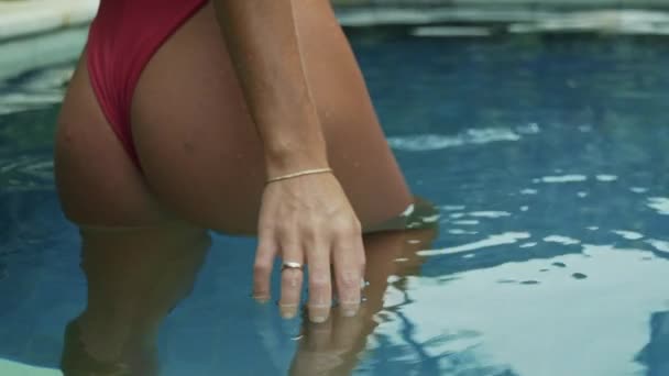 Close-up rear view of the hand of a young girl with a beautiful round ass in a swimsuit recruiting water, rises, water drops in large drops from a womans hand, slow-motion shooting. — Stock Video