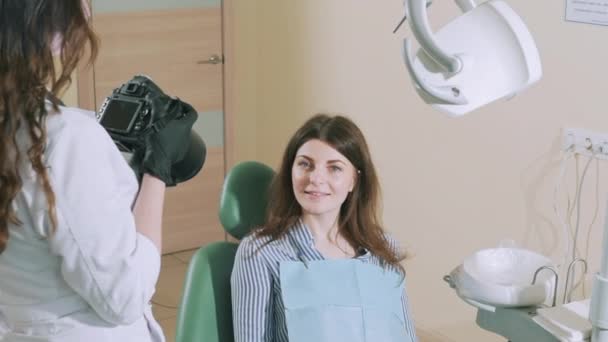 Ciemnowłosa dentysta robi zdjęcia jej pacjenta na profesjonalny aparat po leczenie stomatologiczne do kolażu przed i po. Zwolnionym tempie — Wideo stockowe