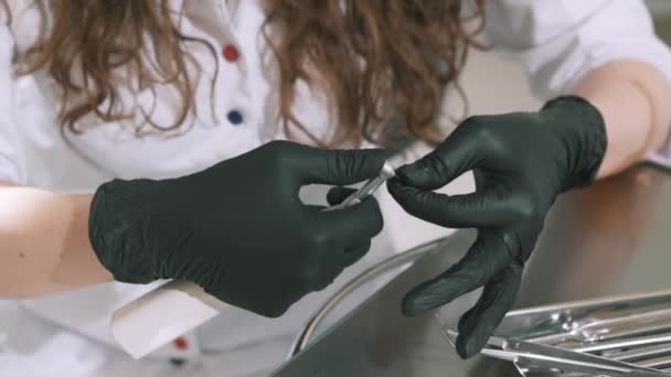 Крупним планом повільний знімок жіночого стоматолога вставляє дриль в дриль, перевіряє справність, працює в стерильних рукавичках. Концепція стоматологів, стоматологічного обладнання, зубів, профілактики та — стокове відео