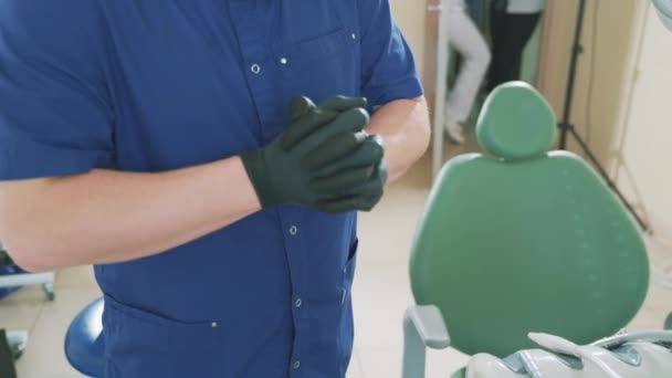 Un gros plan au ralenti de la main des médecins, vêtus de gants médicaux noirs, les redresse, pétrit ses mains avant d'examiner le patient . — Video