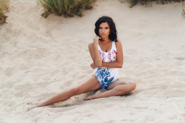 Güzel esmer kız sahilde Okyanusu yakınlarındaki dinlenme bir mayo. Seksi bir vücut ile genç bir kadın portresi profesyonel model poz.