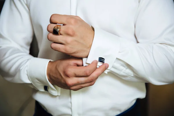 A man in a business suit, white shirt close-up of a cropped frame. The businessman puts on cufflinks, wears a gold finger ring on his finger, an expensive leather belt. — Stock Photo, Image