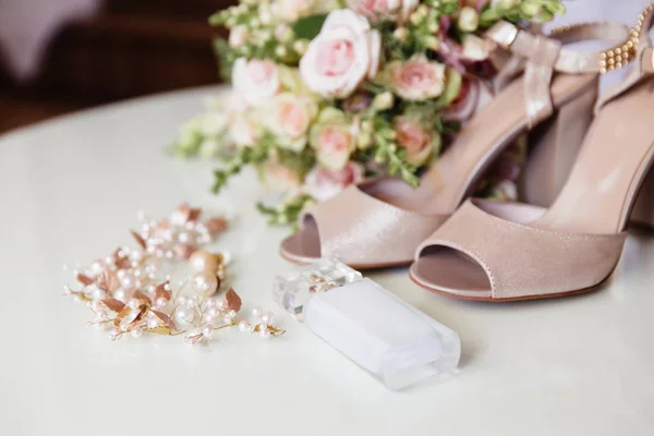 Een rundown plan bijgesneden frame, bruid parfum, juwelen voor de bruiloft hairstyle, oorbellen en blote voeten op een lichte achtergrond. Voorbereiding van het meisje op de huwelijksdag. — Stockfoto