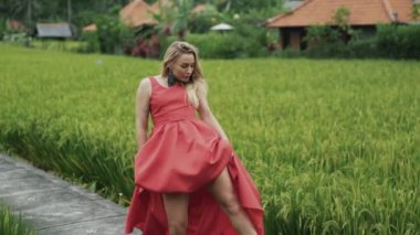 Kırmızı bir elbise ve bir uzun diz boyu etek dans etmek, bir seksi kadın dansçı vücudu wriggles, incelikle kollarını hareket eder ve kafasını wags. Yeşilliklerle çevrili doğa duygusal ve dürtüsel dansında