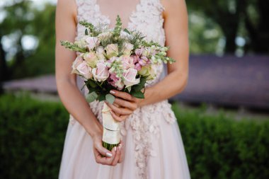 Kırpılan düğün çerçeve bir close-up ihale buket gül gelinin elinde olduğunu. Bir kız bir gelinlik çiçekleri tutuyor.