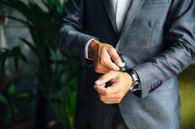 Bir ceket şık ince erkekte kırpılmış bir çerçeve bir close-up saatine görünüyor. İşadamı zaman izliyor, önemli bir toplantı için acele. Kavramı ofis, iş, stil, takım elbise.