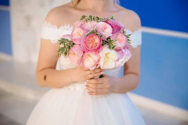 En närbild av en beskuren bröllop ram är en öm bukett med rosor i händerna på bruden. En flicka i en bröllopsklänning håller blommor. — Stockfoto