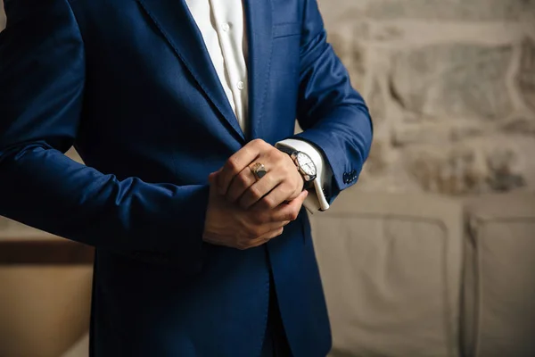Un primer plano de un marco recortado de un hombre en un traje clásico caro mira su reloj. El hombre de negocios tiene prisa y mira la hora. Un hombre guapo con un reloj precioso y un anillo de oro . —  Fotos de Stock