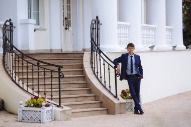 İş koyu elbiseli bir adam merdivenlerde Caddesi ile onun bağdaş ve bekleyen birisi, o endişe ve gülümsüyor için biraz duruyor.