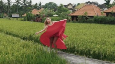 Bir pirinç teras yalnızlık dışında uzun etekli ince bir genç dansçı swirls. Elbise tren rüzgar tarafından geliştirilen, kız hoşlanır özgürlük ve yalnızlık, ağır çekim çekim.