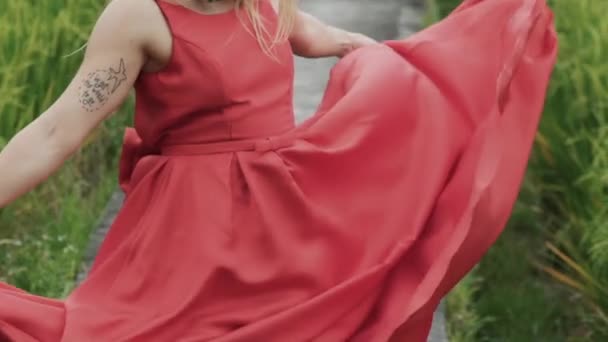 一个特写, 裁剪框架是一个慢动作拍摄, 因为长红裙的丝绸面料发展。女孩握着她的手, 从一边到一边移动, 长白色直欧洲的头发, 太, 在框架. — 图库视频影像