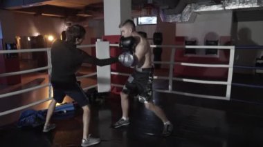 İçinde belgili tanımlık çalmak, grevler, dövüş tekniğin eğitim boks. Genç savaşçı, yan görünüm, hızlandırılmış çekim ile boks koçudur. Boks teknikleri geliştirme tekniği grev,