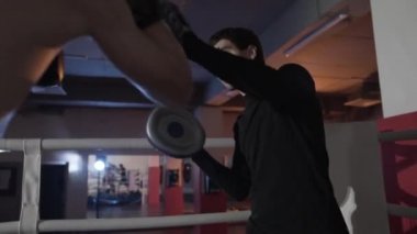 Bir boks antrenörü kırpılmış bir çerçeve bir close-up onun öğrencisi eğitiyor. Mücadele donanımları, boks grevler, boks spor intender, eğitim paws ve eldiven, savaş için hazırlık. Yavaş