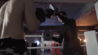 Genç boksörler için belirleyici bir savaş hazırlamak, eğitim aşağıdan görüntüleyin. Boksör antrenörü ile çarpıcı tekniği pratiği yapıyor. Kırpılmış bir çerçeve Close-up.