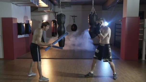 Desportista de treino em câmara lenta no salão de boxe. Preparação do mestre de esportes para a batalha com o campeão. O treinador e o pugilista fazem broches. O conceito de esporte, força, boxe . — Vídeo de Stock