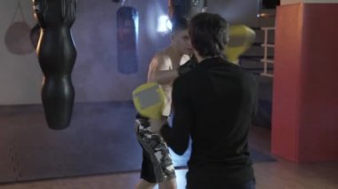 Boksör darbeler ile birlikte koç yerine getirir. Boks pençeleri, boks eldivenleri, spor muhabiri antrenörler bir darbe. Spor, boks, erkekler, darbeler kavramı.