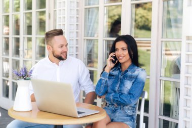 Şık bir çekici kız arkadaşına onu cep telefonundan konuşuyor dışında bir kafede oturuyor. Gülümseyerek, bir dizüstü bilgisayar önünde tutan kız arkadaşıyla bir kafede bir toplantıda bir çevirmen.