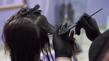Kırpılan çerçeve stilist bir close-up kız keratin nemli saça bir fırça yardımı ile geçerlidir, kompozisyon saç tüm uzunluğu boyunca dağıtır