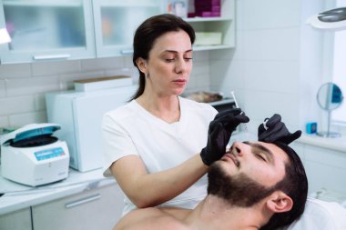 Yakın çekim erkek hasta ve dergi ile el yüz güzelliği enjeksiyonlar sırasında şırınga. Gençleştirme ve hydratation. Kozmetik kavramı, sağlıklı.