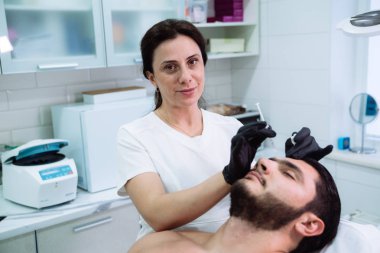 Erkek hasta yüz ve kozmetik eller yukarı yüz güzelliği enjeksiyonlar sırasında şırınga ile kapatın. Botox pislikler, hyaluronik asit enjeksiyonu. Gençleştirme ve hydratation. Kozmetik kavramı
