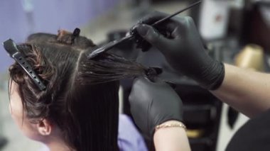 Kırpılan çerçeve stilist bir close-up kız keratin nemli saça bir fırça yardımı ile geçerlidir, kompozisyon saç tüm uzunluğu boyunca dağıtır, bir tarak üzerinden alır