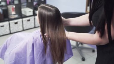 Bir ağır çekim shot dikiz Kuaför bir close-up keratin saç düzleştirme sonucunu değerlendirir, saç altından elini harcıyor, Parlatıcı hayran. Saç, bakım, keratin kavramı