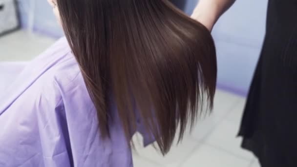 慢动作拍摄特写一个年轻女孩的长黑发。在角蛋白矫直后的灿烂和柔滑的头发。角蛋白的作用, 直发。美容院的概念, 美. — 图库视频影像