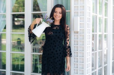 Gülümseyen bir parlak genç Avrupa kadın bir basit beyaz vazoda kır çiçekleri buketi hayranlıkla ev yapımı bir buket tasarım seyir bakar. Ev dekorasyonu, aksesuarlar kavramı