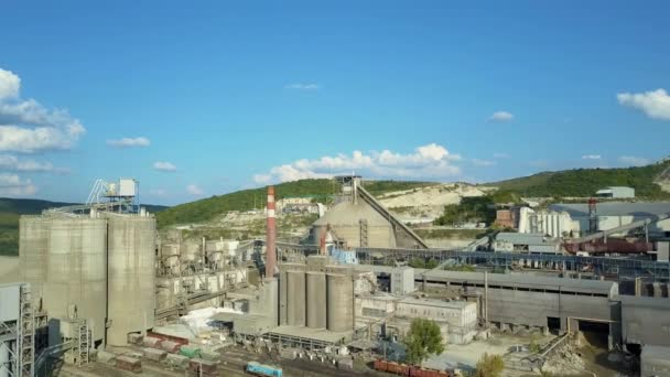 Aerial view of cement factory, large industrial building in the mountains. Concept of cisterns, pipes, metal structures, concrete production. Daytime footage with a beautiful blue sky. — Stock Video