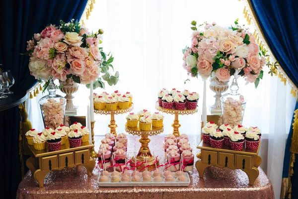 Barra de caramelos, una mesa con dulces y postres en la mesa. Buffet con deliciosos cupcakes, pasteles, galletas, flores . — Foto de Stock