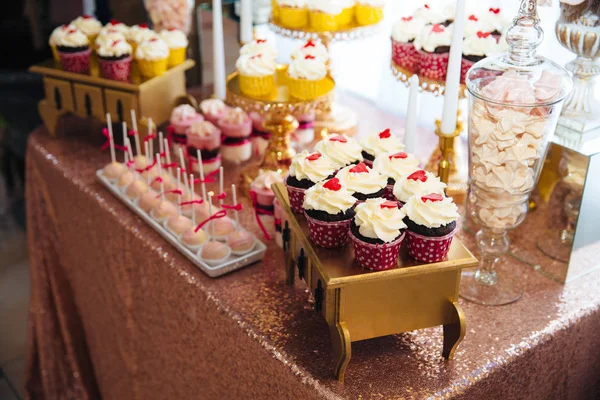 Barra de caramelos, una mesa con dulces y postres en la mesa. Buffet con deliciosos cupcakes, pasteles, galletas, flores . — Foto de Stock