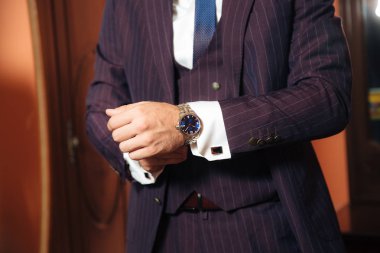 Şık bir işadamı kırpılmış bir çerçeve bugün evleniyor, şık bir takım elbiseyi giy, beyaz bir gömlek giyer ve şık pahalı deri saatleri, kol düğmeleri onun kol bağlar yıkık planıdır.