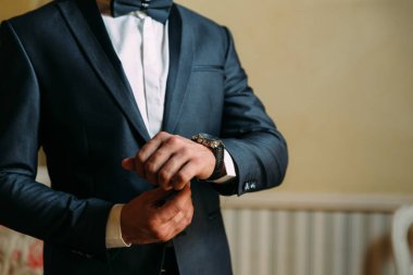 Bir adamın pahalı bir klasik kostüm kırpılmış bir çerçeve bir close-up saatine görünüyor. İşadamı acelesi var ve o zaman görünüyor. Yakışıklı bir adam değerli bir saat ve bir altın yüzük.