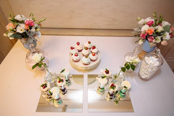 Vista superior da barra de doces, uma mesa com doces e sobremesas na mesa. Buffet com deliciosos cupcakes, bolos, biscoitos, flores . — Fotografia de Stock