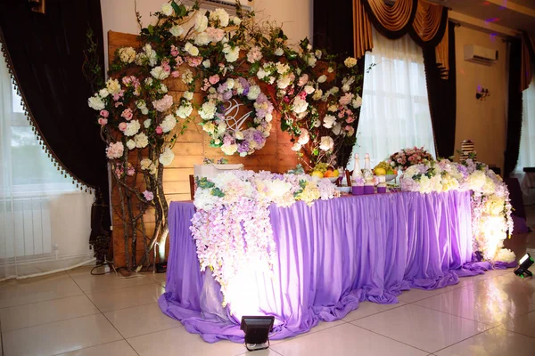 The concept of a wedding celebration, celebration of lovers, decor, flowers, fabrics. The table of the newlyweds is decorated with flowers, candles and fabrics.