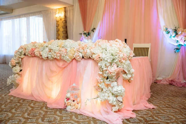 O conceito de uma celebração de casamento, celebração de amantes, decoração, flores, tecidos. A mesa dos recém-casados está decorada com flores, velas e tecidos. . — Fotografia de Stock