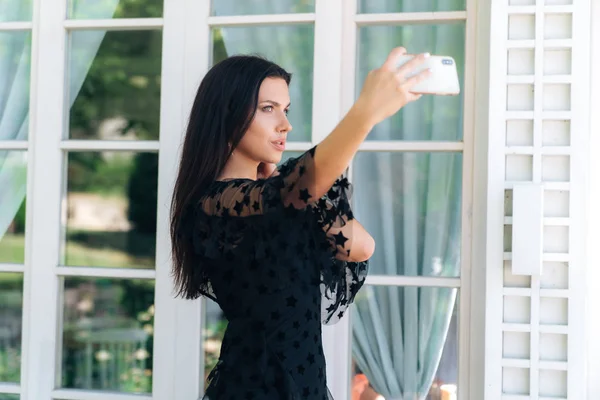 Fashionable beautiful young European girl makes selfie on her smartphone. Concept photo, gadgets, people, technology. — Stock Photo, Image